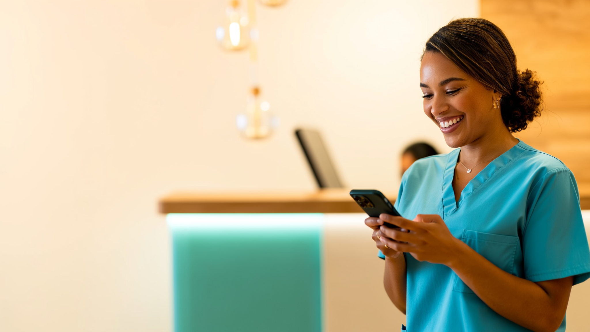 Recepcionista de clínica sorrindo enquanto bate o ponto pelo celular